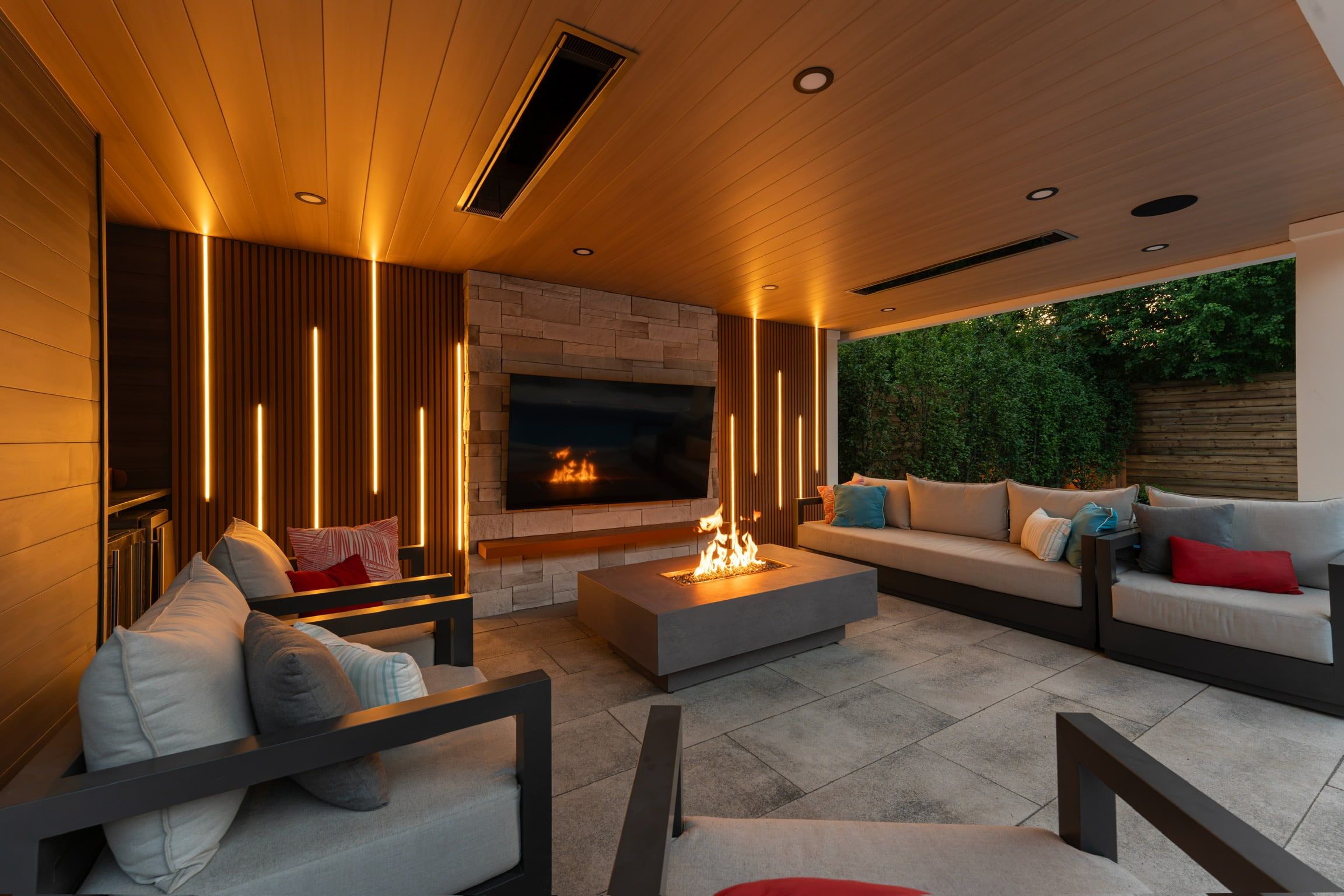 Inside the cabana: vertical light lines in the slat walls beside the stone fireplace and TV.