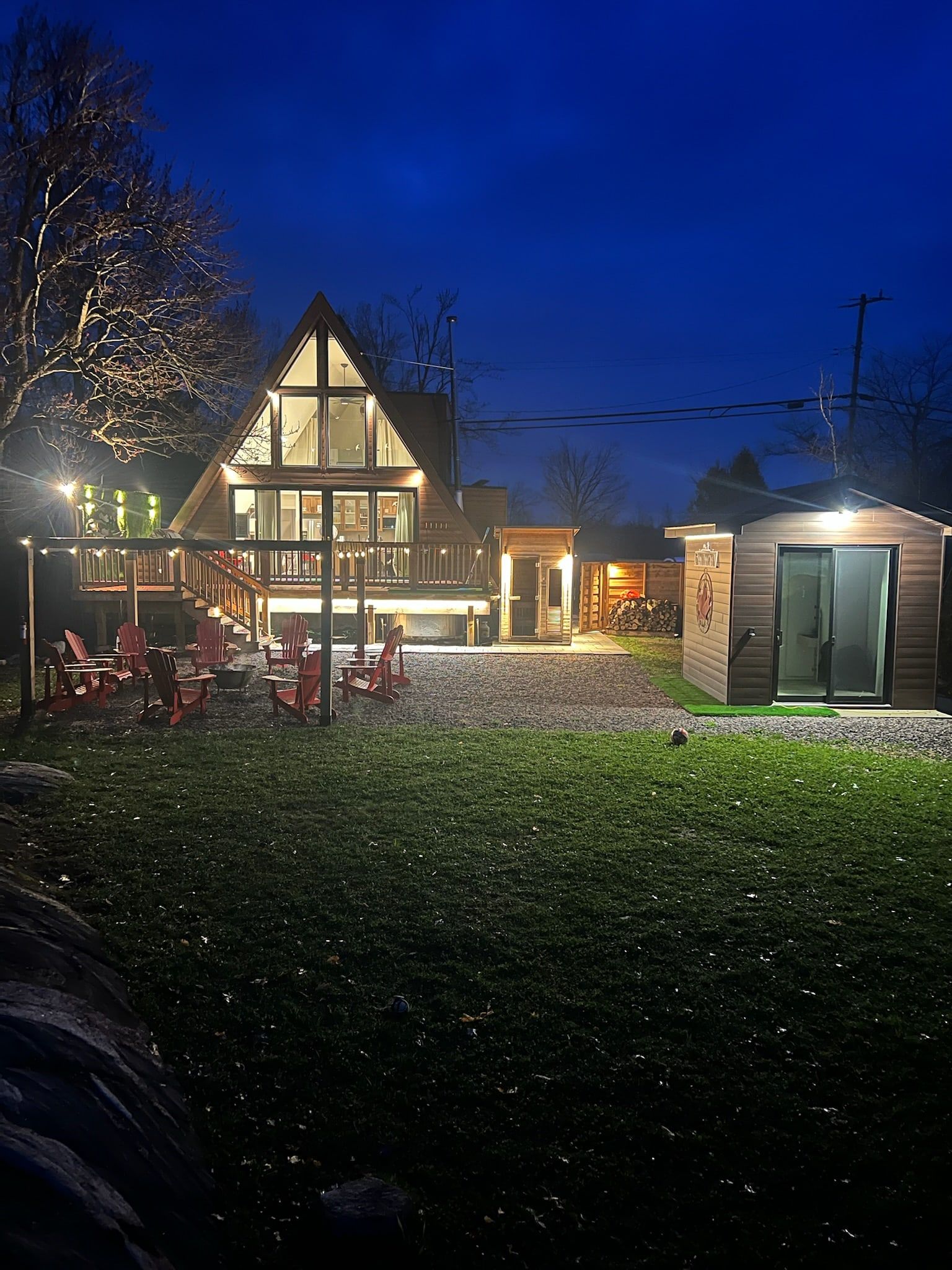 The cottage's glass gable at night, seen across the yard.
