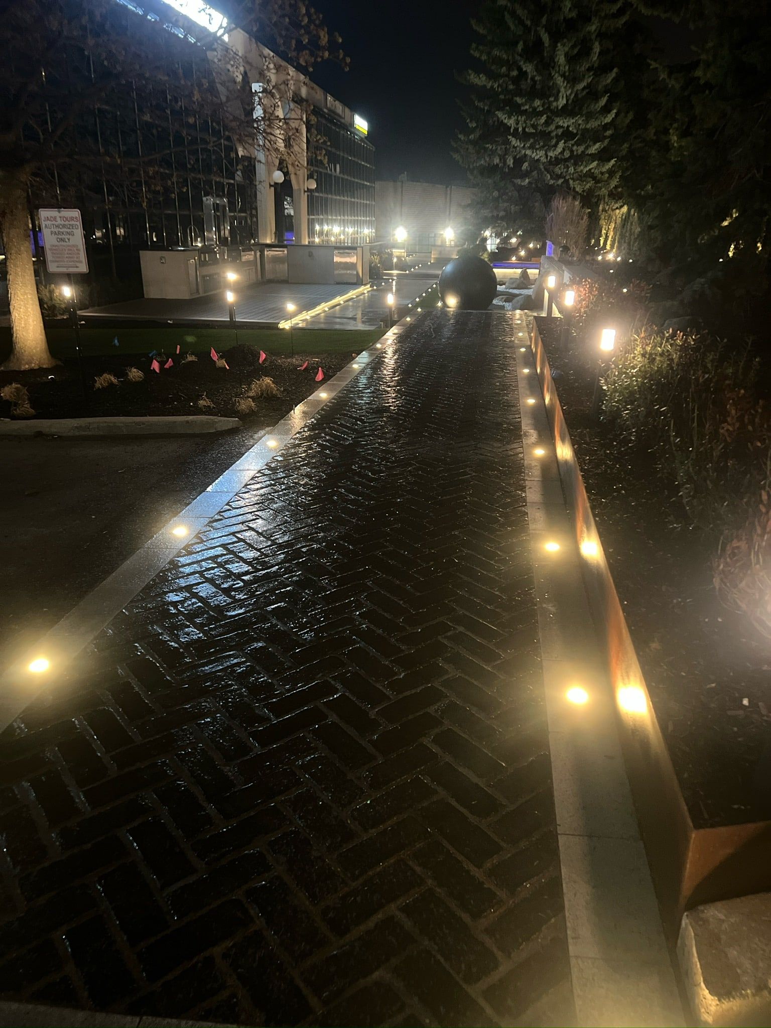 Recessed lights along a herringbone path at night.