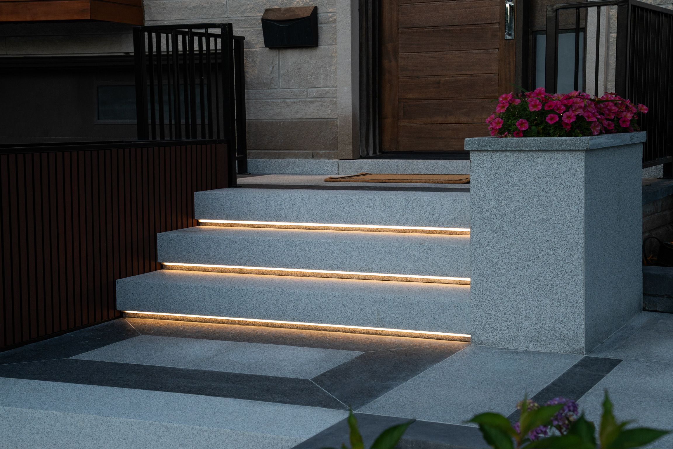 Granite entry steps at dusk with a warm line of light under each step.